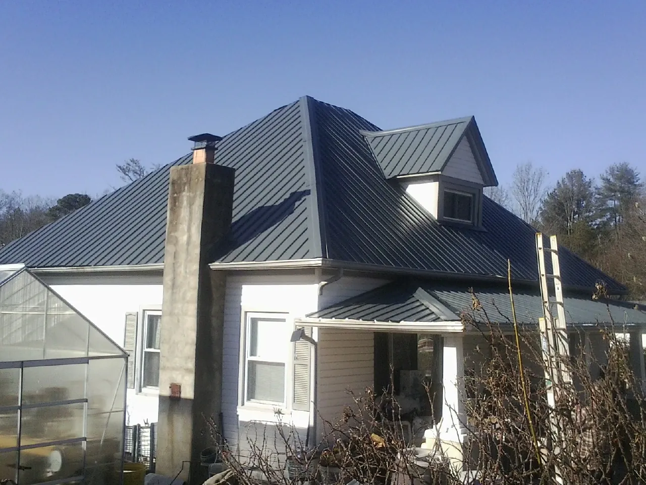 Dark blue standing seam metal roof on a white farmhouse with dormer — Slate & Tile Roof Repair by Roofing Brothers in Amston