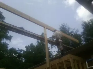 Carpenter setting a ridge beam over a new addition frame — Ice Dam Removal by Roofing Brothers in Amston