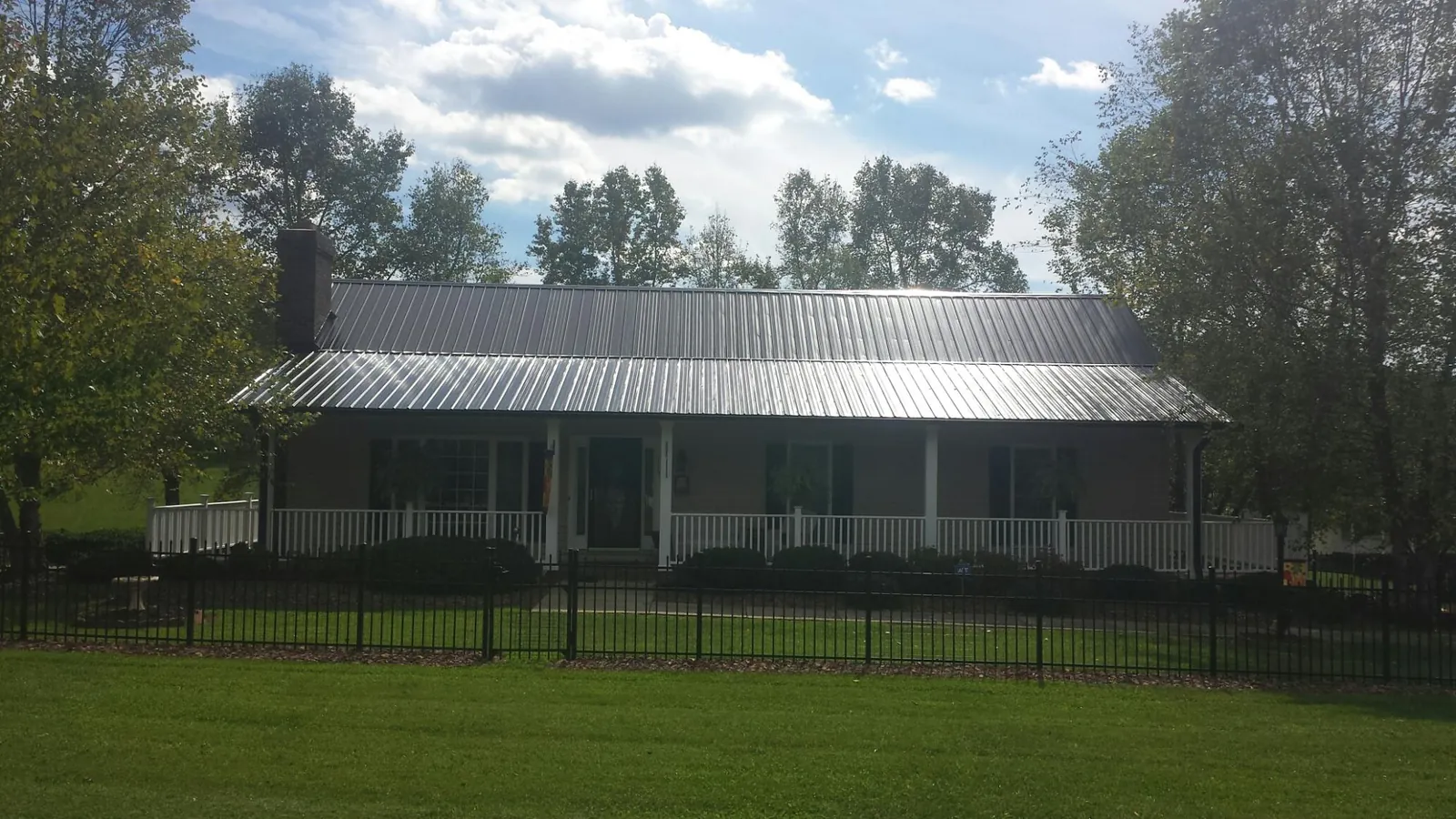 Gray metal roof on a brick ranch with a full width front porch — Gutter Guard Installation work by our crew in Amston