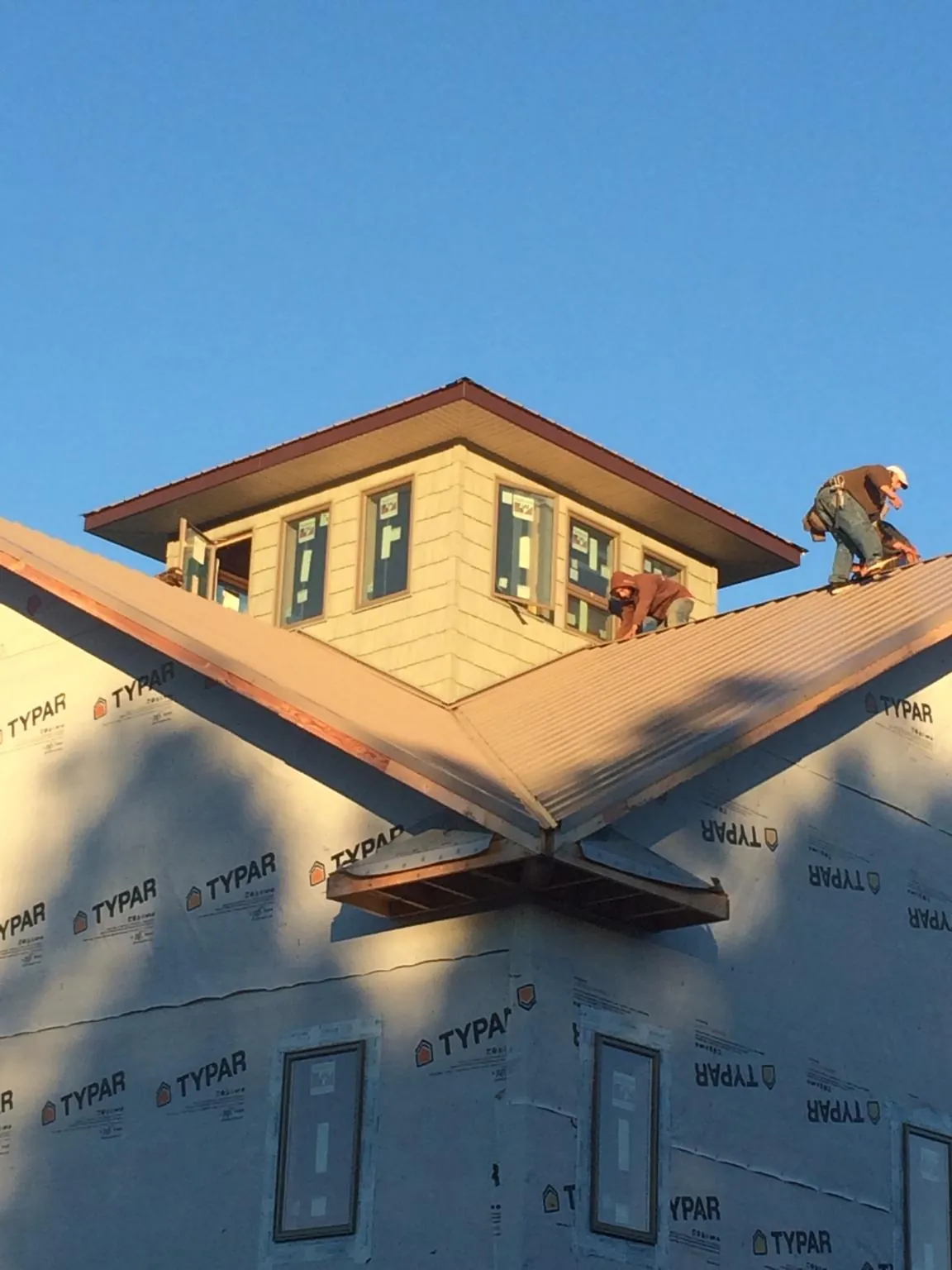Roofers working around a rooftop cupola on a new metal roof at sunset — Roof Waterproofing in Amston by Roofing Brothers